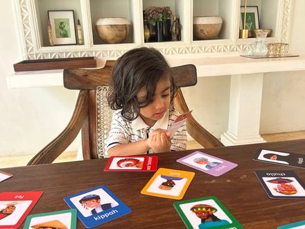 A young child looking through head coverings flashcards